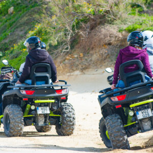 Two quad bikes, with two people driving each quad bike. The bikes are being driven in Gozo.